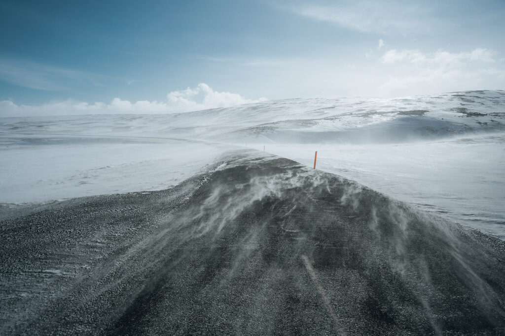 Wind and snow covering a road during a storm in Iceland.