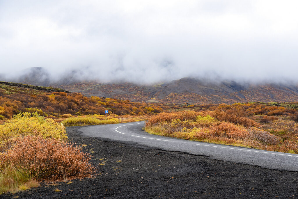 Fog descending from the mountains in Iceland towards a road.