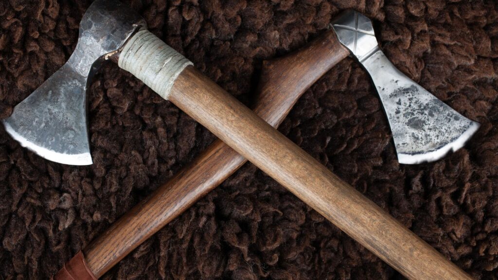 A pair of Viking battle axes laid in a cross position on sheep’s fur