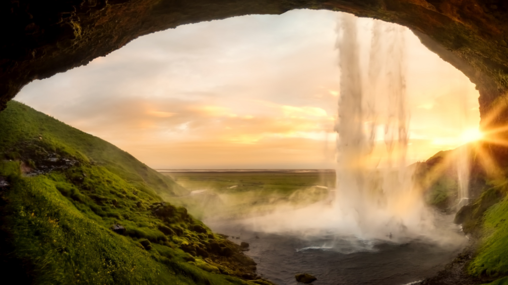 The view from behind Seljalandsfoss waterfall in Iceland at sunset. 